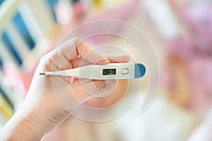 Close-up medical thermometer, Parent measuring temperature of ill kid, 1 years old toddler girl gets high fever lying on bed.