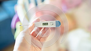 Close-up medical thermometer, Parent measuring temperature of ill kid, 1 years old toddler girl gets high fever lying on bed.