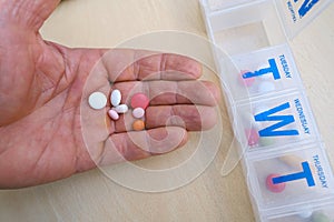 close-up medicinal capsules, pills, vitamins in male palm, plastic pillbox organizer for week, concept controlling regular