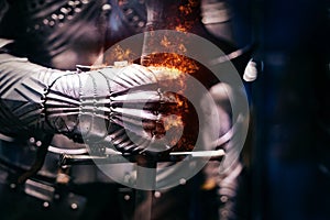 Close up of a Medieval steel armour with iron glove hand bursting with flames of fire