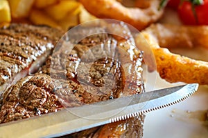 Close up of medium rare 10 ounce rump steak with steak knife