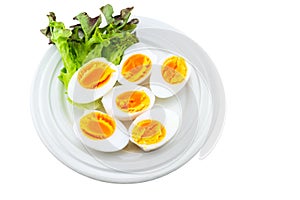 Close up medium soft boiled duck egg portion and green salad in white dish on white  background