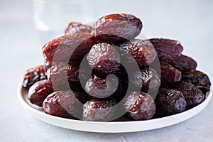 Close up of Medjoul dates in a white plate on a gray background