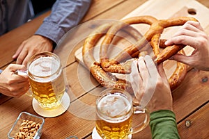Close up of men drinking beer with pretzels at pub