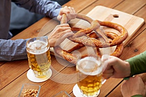 Close up of men drinking beer with pretzels at pub