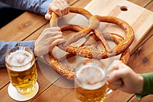 Close up of men drinking beer with pretzels at pub