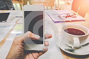 Close up of men hands holding touching mobile phone with blank copy space for your text message on wood in the cafe with light Sun