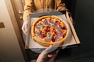 Close-up men`s hands pass the order to pepperoni pizza. Food delivery to any place