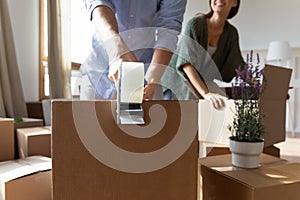 Close up man sealing box with adhesive tape, moving day