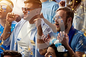 Close-up of men, sport fans emotionally cheering up favourite football, soccer team of greece at stadium during game