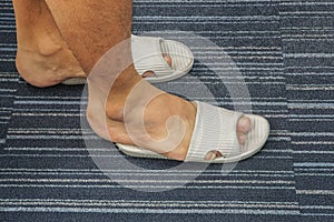 Men wear too tight sandal on his feet in the house