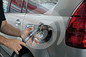 Close-up of a mens hand refilling the car with a gas pump. Man inserting nozzle in fuel cap of a car