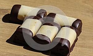 typical dutch sweet cookie called & x22;mergpijpje& x22; covered with white marzipan, on a wooden background