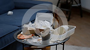 Close up of messy table, leftover food, dirty dishes in empty living room