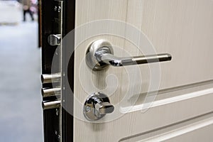 Closeup of metal doorhandle and look on white door