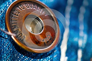 Close up of a metal button on a pair of jeans