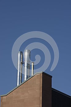 Close up metal chimneys on the factory roof.