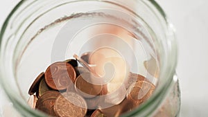 Close-up of metal coins falling into a piggy bank. Eurocents are thrown into the piggy bank.