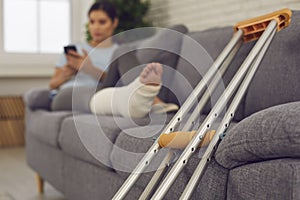Close-up of metal crutches for walking and young woman with broken leg