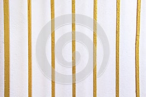 Metal fence with gold paint on old white concrete wall background