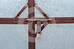 Close-up of a metal gate with a rusty crossbar lock