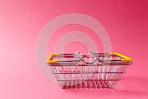 Close up of metal grocery basket for shopping in supermarket with lowered handles and yellow plastic elements isolated photo