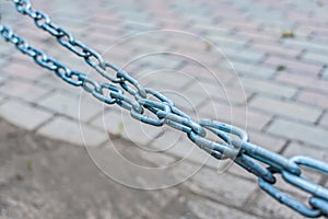 Close-up of a metal long stretched chain over the sidewalk