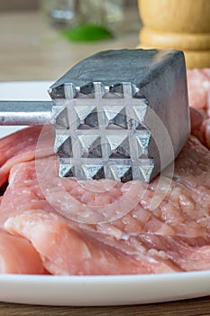 A close up of a metal meat tenderizer hammer utensil