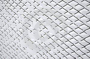 Close-up metal mesh covered with a thick layer of snow in the cells