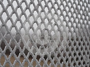 Close-up metal mesh covered with a thick layer of snow in the cells