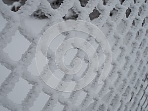 Close-up metal mesh covered with a thick layer of snow in the cells