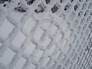 Close-up metal mesh covered with a thick layer of snow in the cells