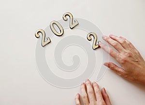 Close-up of metal numbers 2022 and hand on white background. Concept of change year 2021 to 2022