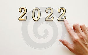 Close-up of metal numbers 2022 and hand on white background. Concept of change year 2021 to 2022