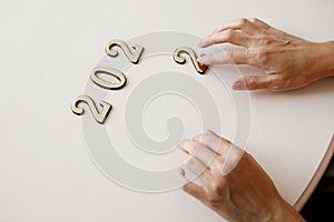 Close-up of metal numbers 2022 and hand on white background. Concept of change year 2021 to 2022