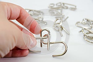 Close-up of a metal puzzle in a female hand on a white background. Concept to solve the puzzle.