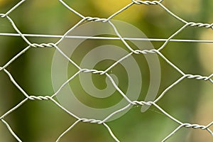 Close up of metal wire mesh fence with a green natural background