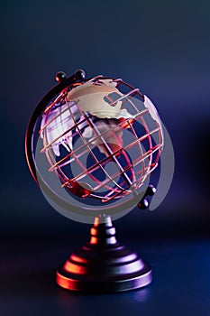 Close up metallic model of a globe with map in blue and red neon light. Bipolarity of the world. Geography concept