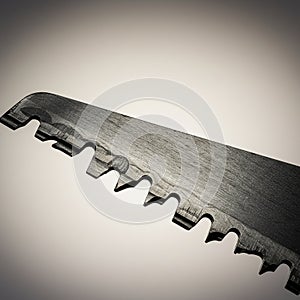 Close-up of a metallic saw blade with a series of jagged teeth designed for cutting.