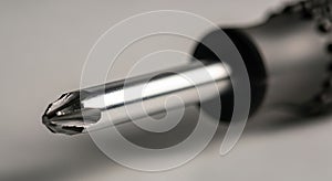 Close-up of a Metallic Screwdriver Tip in Sharp Focus on Gray Background