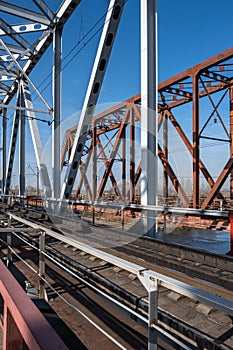 Close-up of the metalwork of a railway bridge over a river with a permitted pedestrian crossing