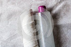 Close-up of micellar water or facial toner with cotton pads on white tissue
