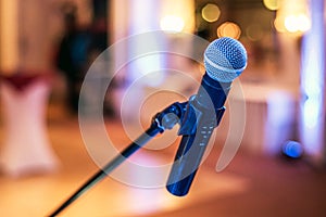 Close up of microphone in concert or conference hall with blurred lights at background