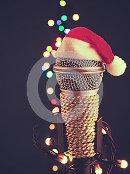 Close up of a microphone with the hat of Santa and blurred lights background