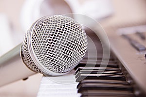 Close up on a microphone during recording session with a singer, piano in the background, music studio.