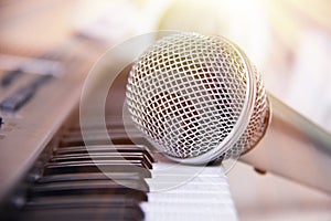 Close up on a microphone during recording session with a singer, piano in the background, music studio, light leak style.