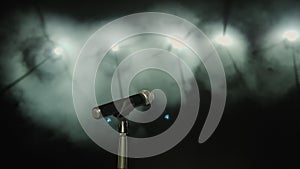 Close-up of microphone on stage with white lighting and smoke.