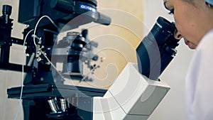 Close up of a microscope being watched through by a female scientist
