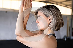 Close-up of a mid adult woman in an eagle pose or garudasana during her vinyasa flow yoga practice in a gym