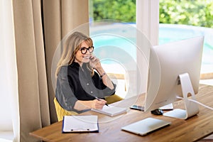 Attractive mid aged woman sitting at home and using compter for work